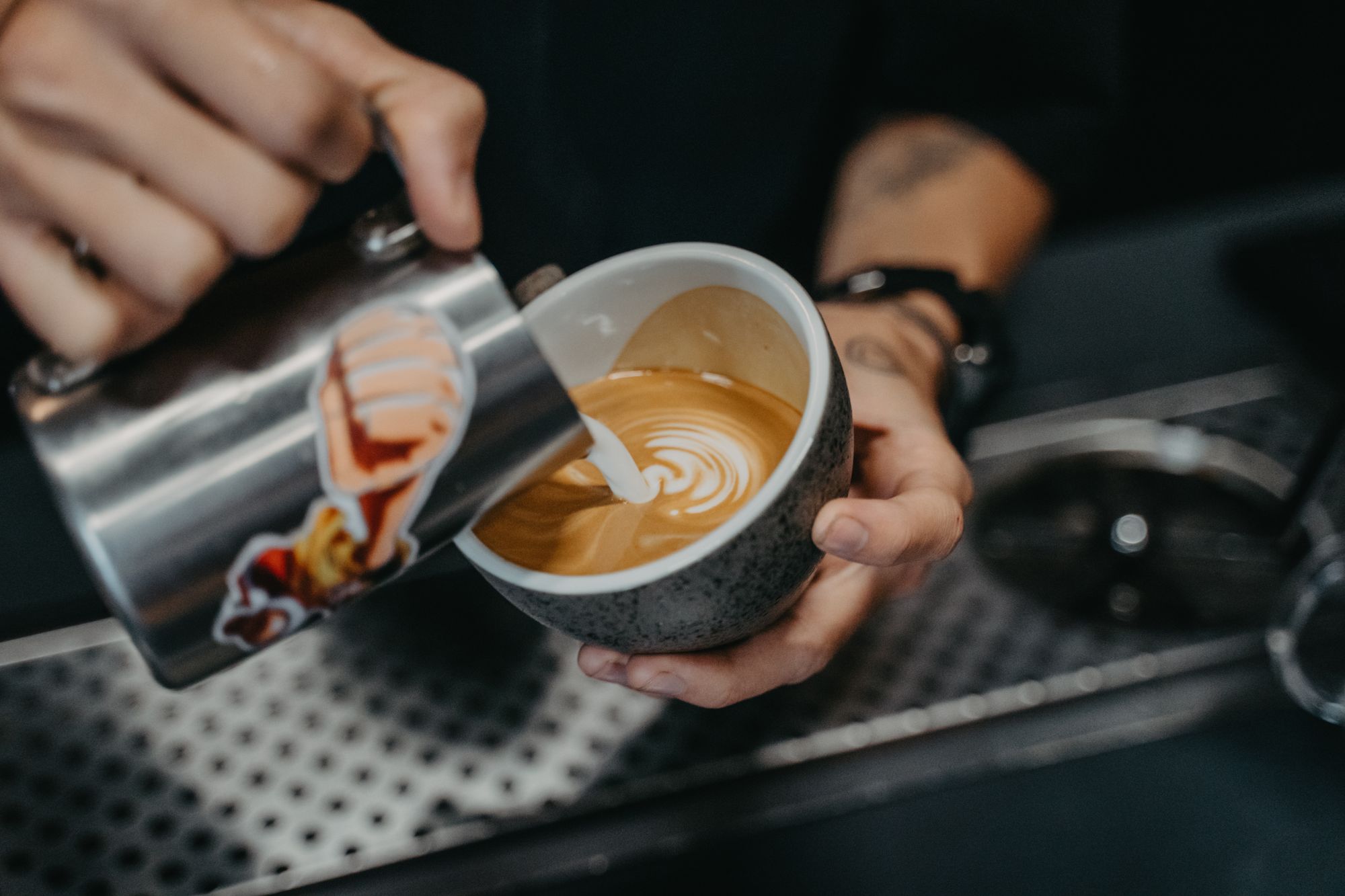 Barista gießt Milch in Kaffee